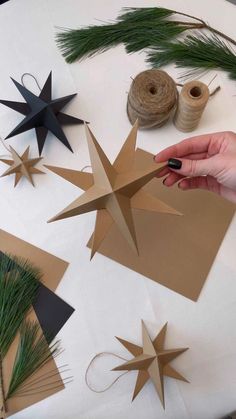 someone is making christmas decorations out of brown paper and twine on a white table