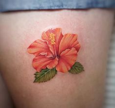 an orange flower with green leaves on the thigh