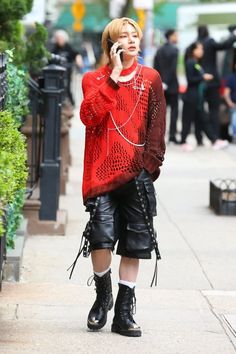 a woman is talking on her cell phone while walking down the street in leather shorts