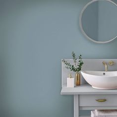 a white sink sitting under a round mirror next to a wooden table with candles on it