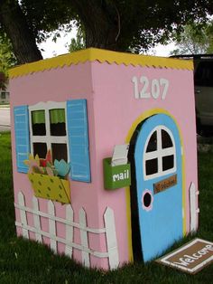 a toy house made out of cardboard sitting in the grass