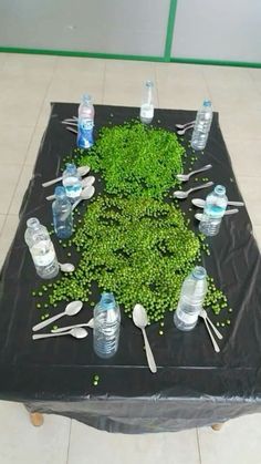 a table topped with lots of water bottles and utensils covered in green leaves