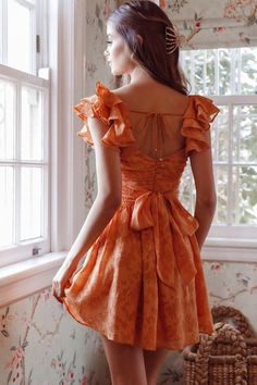 Orange textured dress Ruching detail in bodice Surplice neckline Ruffle shoulders Wide waistband Waist tie Scooped back with string tie Zipper in back You'll be the belle of the ball in our gorgeous Lola dress. We are in love with the ruching detail throughout the bodice and its flirty, layered ruffle shoulders. Perfect for a special birthday celebration or a garden wedding teamed with perspex heels and a clutch. Cute! MODEL INFO Model is wearing size XS Height: 5'8" Bust: 31" Waist: 23.5" Hips: Short Colorful Dress, Peach Orange Dress, Little Yellow Dress, Orange Spring Dress, Ruffle Homecoming Dresses, Orange Aesthetic Dress, Orange Graduation Dress, Fall Orange Dress, Orange Dress Aesthetic