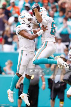 miami dolphins football players jumping up in the air to catch a ball during a game