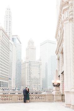 an engaged couple standing in front of tall buildings