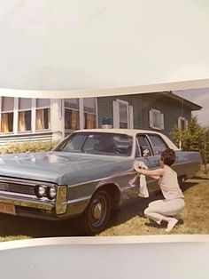 a woman kneeling down next to a car in front of a house