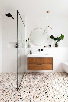 a bathroom with a sink, mirror and bathtub next to a shower stall that has plants on the wall