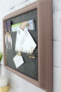 a bulletin board mounted to the side of a wall with magnets and paper clips on it