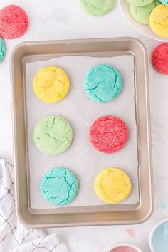 colorful cookies are on a baking sheet next to bowls