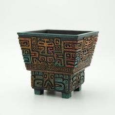 a small pot with designs on it sitting on a table