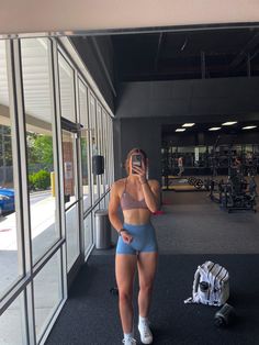 a woman is taking a selfie in front of a gym with her cell phone