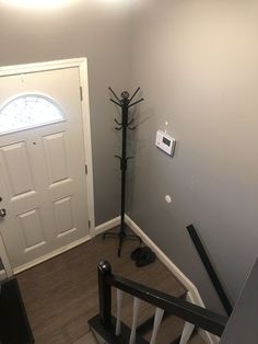 an entryway with stairs and a clock mounted to the wall next to a door