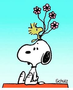 a cartoon snoopy with flowers on top of it's head, sitting on a table