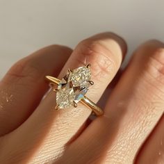 a woman's hand holding an engagement ring with two pear shaped diamonds on it