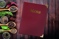 a red menu sitting on top of a wooden table next to spoons and spices