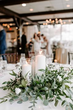 candles and greenery on a table at a wedding reception