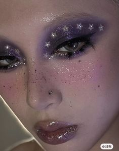 a woman with stars painted on her face and makeup is looking at the camera while wearing purple