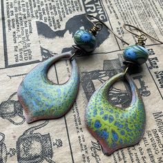 * These beauties feature a stunning enameled component by artist Linda Younkman. I added the poly clay Humblebead to highlight the lovely blues and greens. Pretty!  * earrings measure 3 inches in full and are a bit heavier than most earrings * Designed in Poestenkill NY * NOTE: Wearing in water or to the gym is not recommended  * NOTE:  As with most jewelry , do not force an adjustment if a section becomes mis-aligned. Just give a gentle tug or wiggle and it will straighten out easily. * DISCLAIMER: other items used in photo are not for sale, nor are they included in any purchase. Vintaj Jewelry, Poly Clay, Blues And Greens, Artisan Earrings, Bead Stringing, Pretty Earrings, Enamel Jewelry, Earrings Boho, Boho Earrings