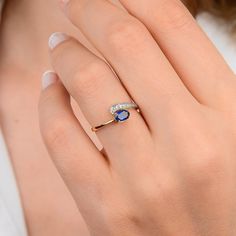 a woman's hand with a ring on it and a blue stone in the middle