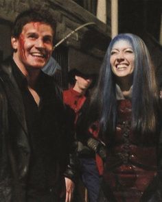 two people standing next to each other with blood on their faces and hair, smiling