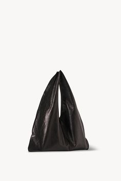 Unstructured mini bag in shiny coated leather with draping silhouette and fluid construction. The Row Bindle, Bindle Bag, Eyeglass Jewelry, Towel Scarf, Small Shoulder Bags, Heeled Loafers, Small Shoulder Bag, Pump Sandals, Leather Pouch