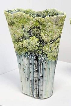 two vases sitting on top of a white table next to each other with trees painted on them