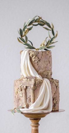 a three tiered cake with white icing and greenery on top, sitting on a wooden stand