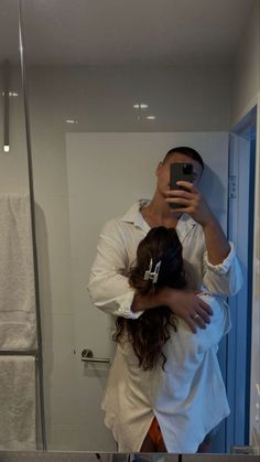 a man taking a selfie in front of a mirror with his arm around a woman's head