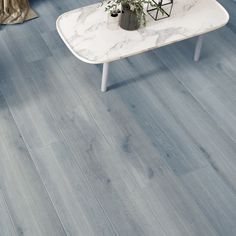 a living room with blue wood flooring and marble table in the middle, next to a couch