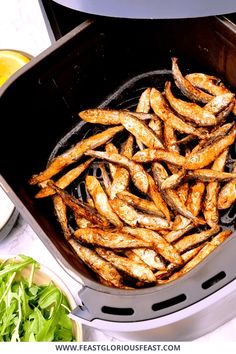 fried fish being cooked in an air fryer with lettuce on the side