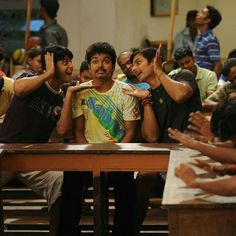 a group of people standing around each other in front of a wooden table with their hands up