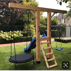 a wooden swing set with a blue slide and swings in the grass next to it