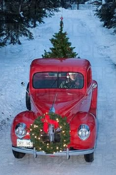 an old red car with a christmas tree on the back