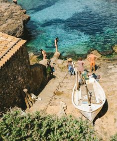 people are standing on the rocks near a boat