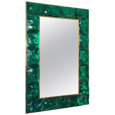 a mirror with green glass and gold trimmings on the edges, in front of a white background