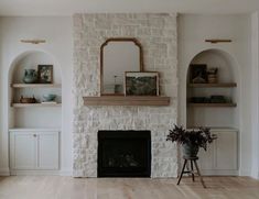 an empty living room with a fireplace and shelves