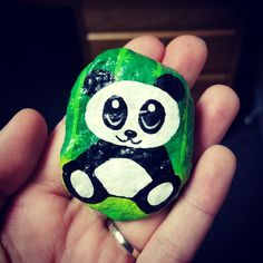 a hand holding a rock with a panda bear painted on it