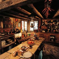 an old fashioned kitchen with wooden table and chairs in the center, surrounded by pots and pans