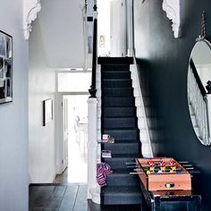 a black staircase leading up to the second floor with a game table on top of it