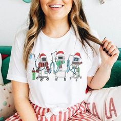 Looking for a way to show off your holiday spirit AND your profession? This Christmas ventilator T-shirt is the perfect way to do both! Whether you're hitting the town or working a long shift, you'll be sure to spread some cheer in this festive shirt. This tee is printed DTG on high-quality Bella + Canvas brand tees. Our soft tees are perfect for wearing on their own and easy to dress up with a cardigan and a necklace. Made of 100% cotton for solid colors. Heather colors and sports grey include Respiratory Christmas Door, White Novelty Tops As Gift, White Novelty Tops For Gifts, White Novelty Tops As A Gift, Fun White Christmas Tops, Fun White T-shirt For Holiday, Funny White T-shirt For Holiday, Nicu Respiratory Therapist Shirt, Respiratory Therapy Shirts