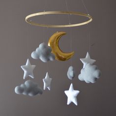 a mobile with stars, moon and clouds hanging from it's sides on a gray wall