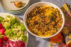 two bowls filled with food on top of a table next to plates of broccoli and radishes