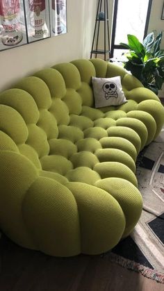 a large green couch sitting on top of a hard wood floor next to a window