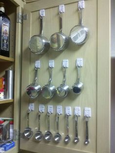 there are many spoons and measuring spoons on the wall next to each other