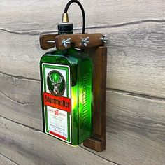 a green bottle hanging from the side of a wooden wall with a light on it