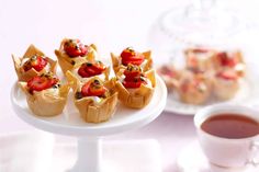 small appetizers on a white plate next to a cup of tea