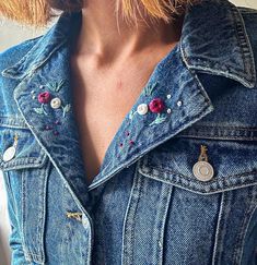 a close up of a person wearing a jean jacket with flowers on the front and back