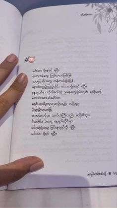 a person is holding an open book with writing on the pages in thai and english