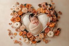 a newborn baby wrapped in a heart surrounded by flowers and pumpkins