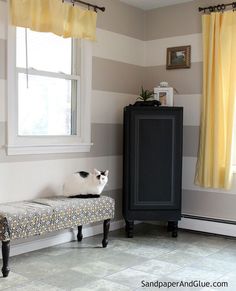 a black and white cat sitting on top of a bench in front of a window